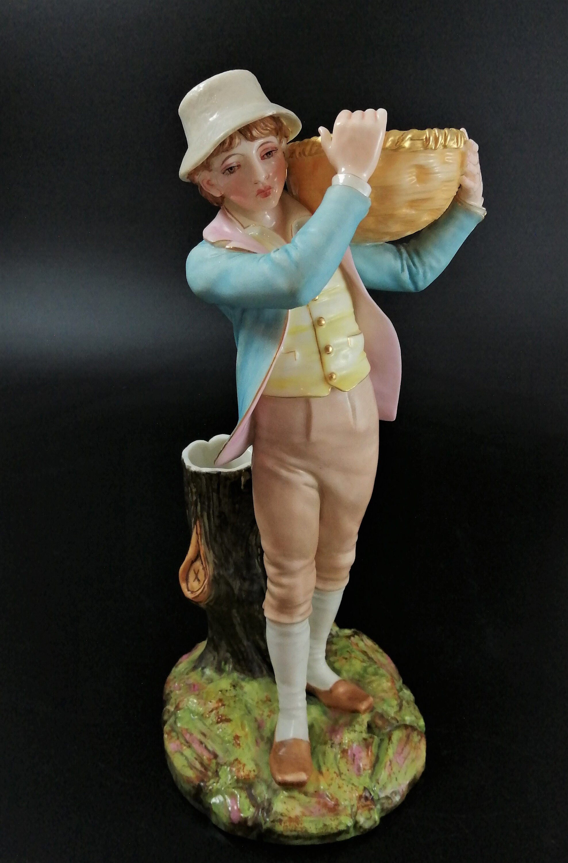 Antique Royal Worcester figural spill holder,of boy carrying basket,James Hadley