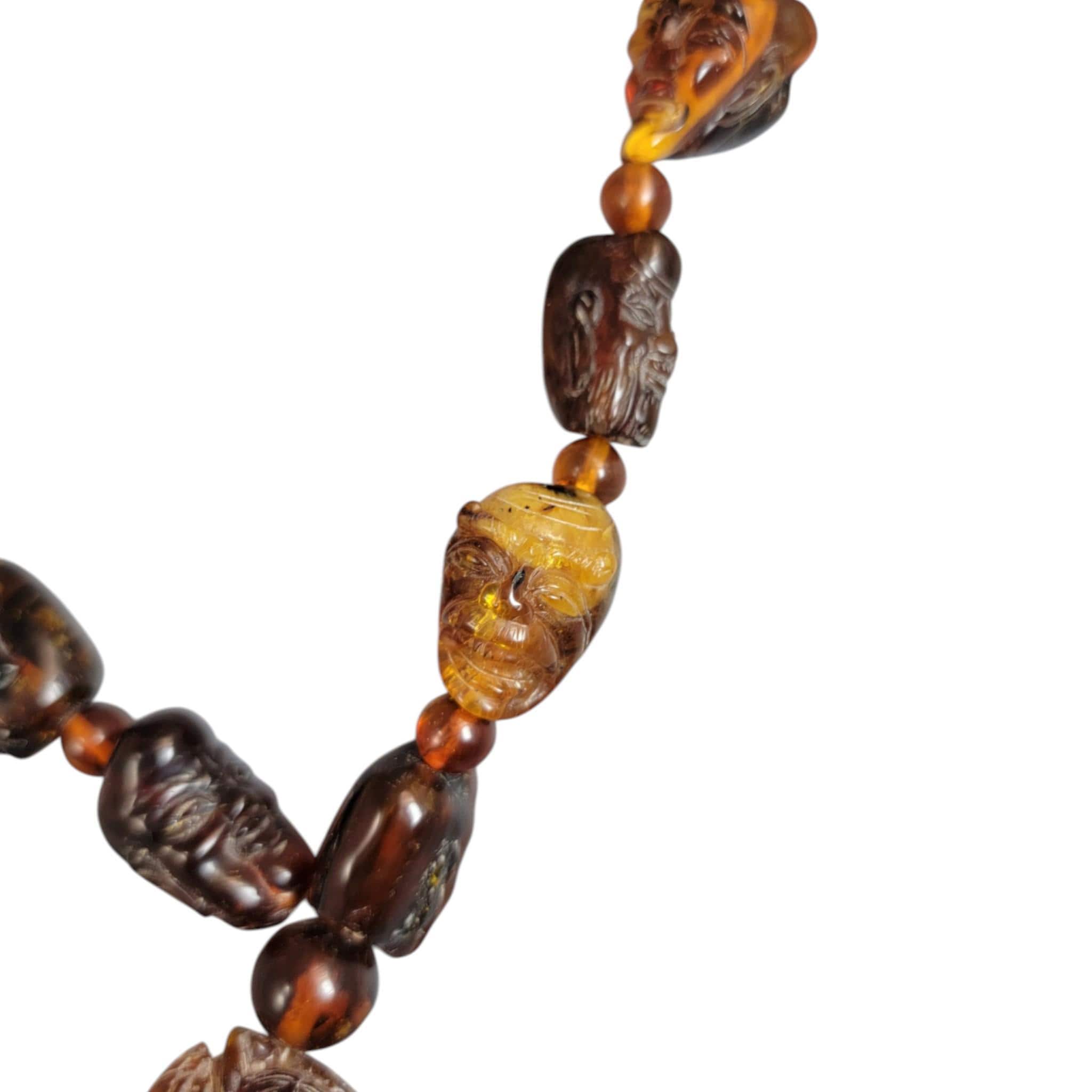 Chinese carved amber necklace with luohan heads and figural pendant, c. 1870
