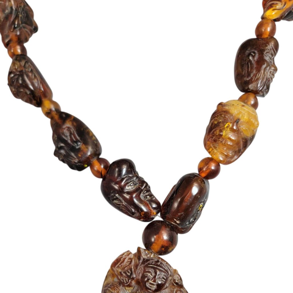 Chinese carved amber necklace with luohan heads and figural pendant, c. 1870