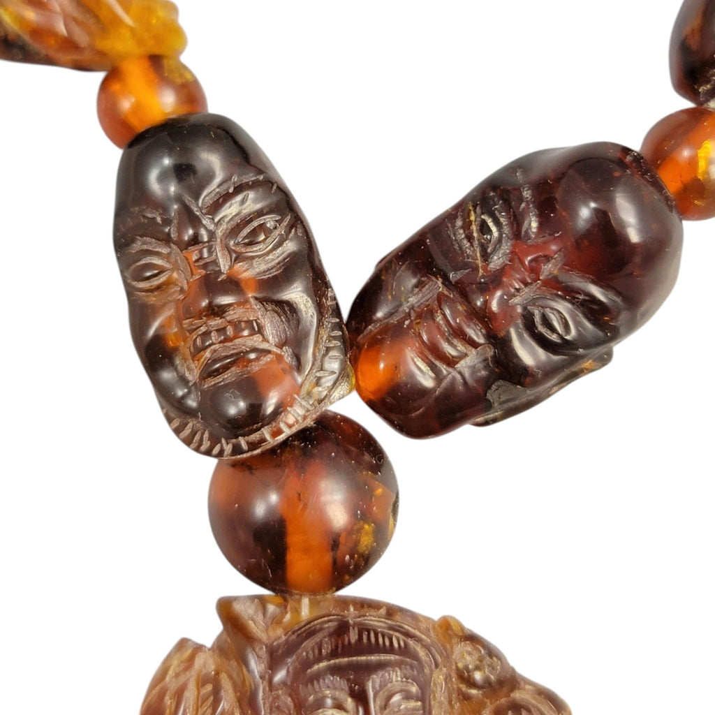 Chinese carved amber necklace with luohan heads and figural pendant, c. 1870