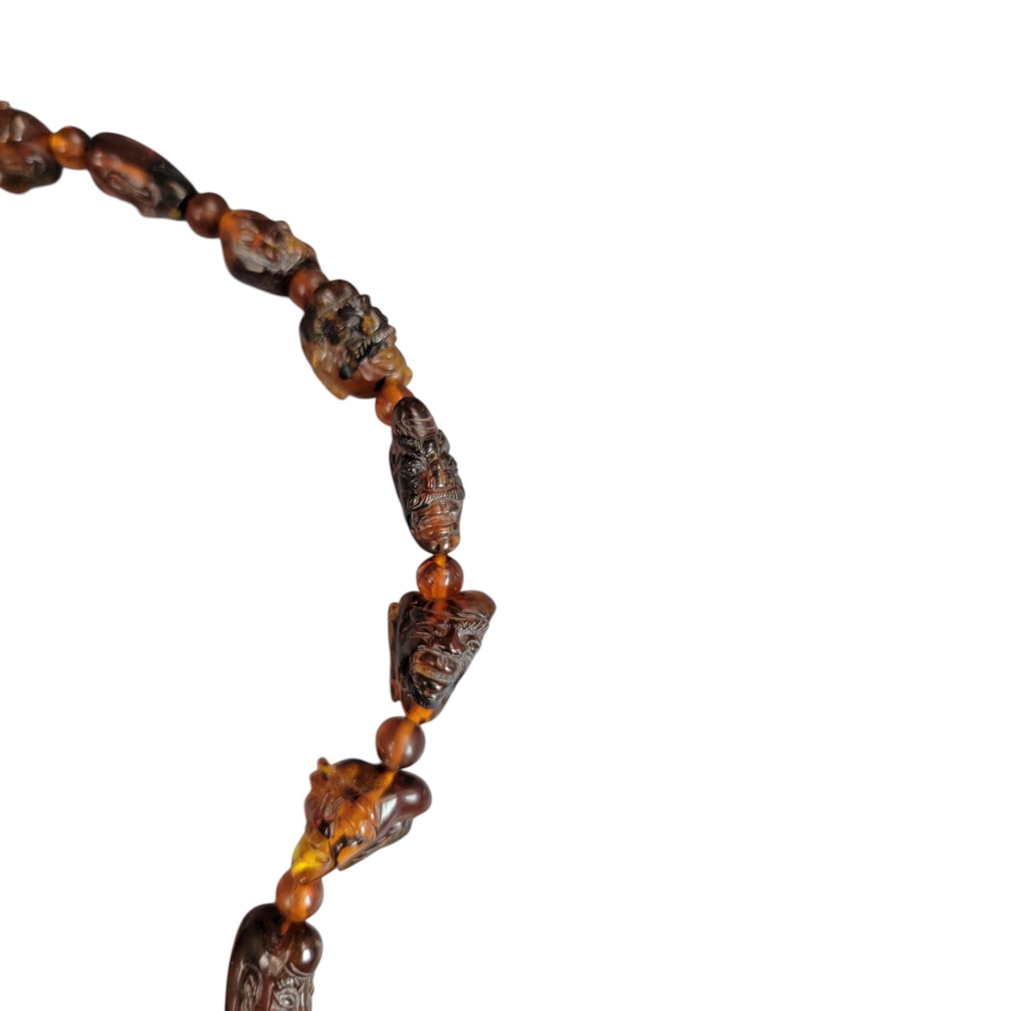 Chinese carved amber necklace with luohan heads and figural pendant, c. 1870