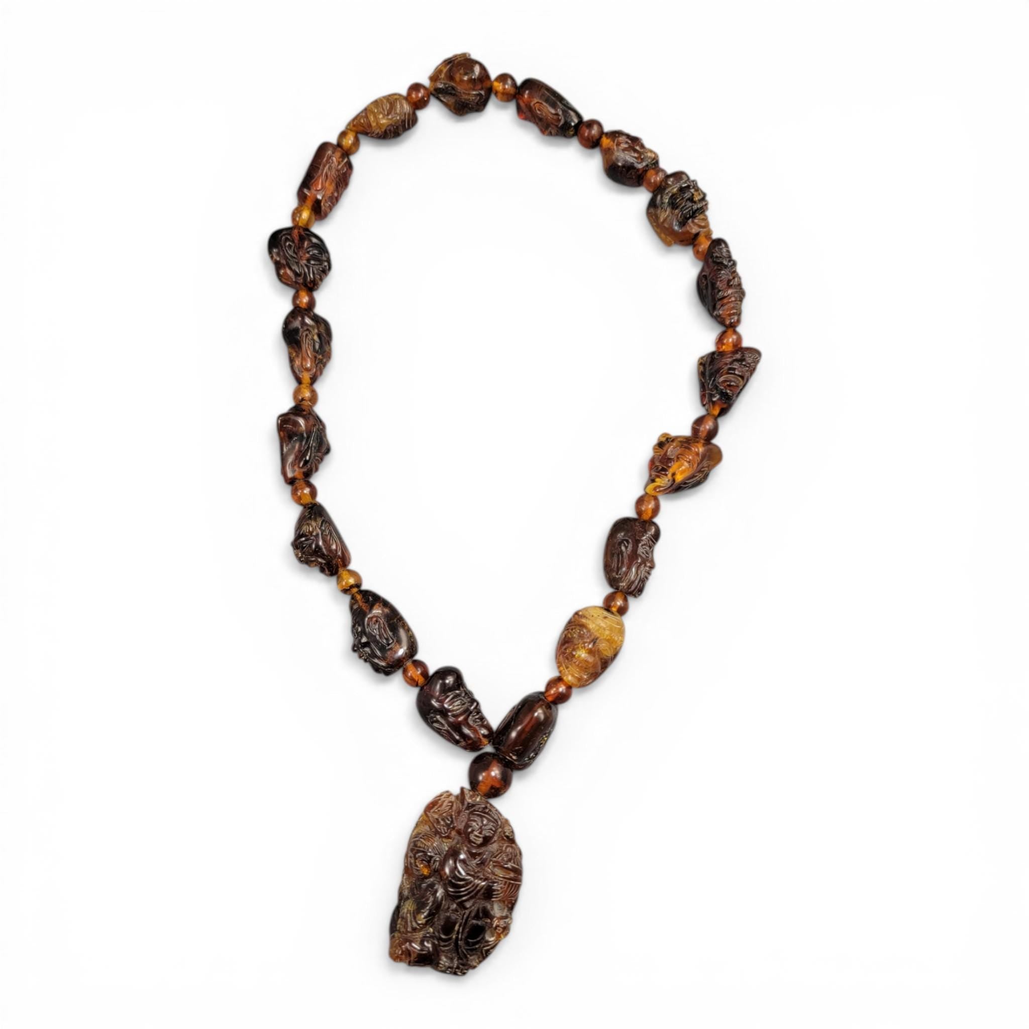 Chinese carved amber necklace with luohan heads and figural pendant, c. 1870