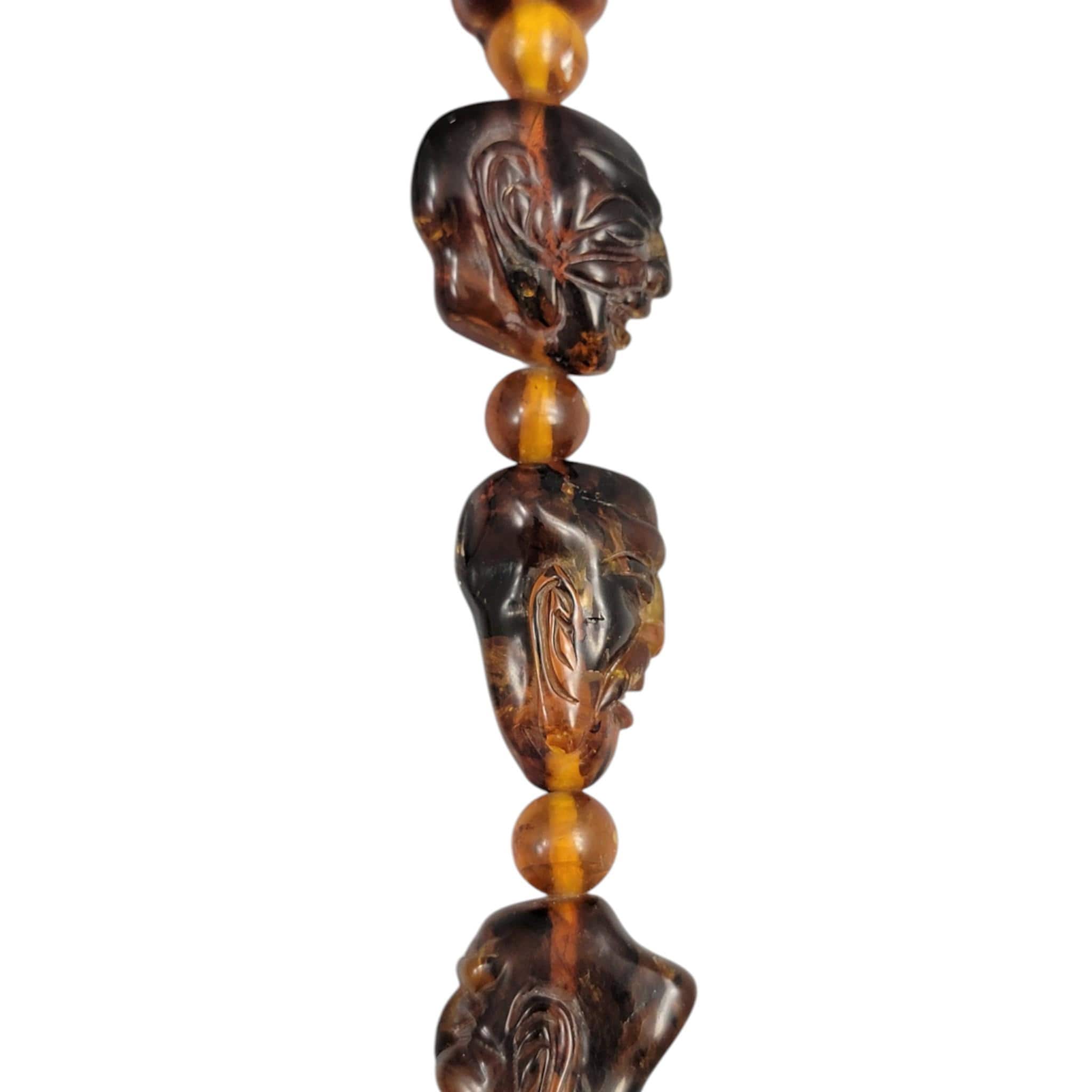 Chinese carved amber necklace with luohan heads and figural pendant, c. 1870