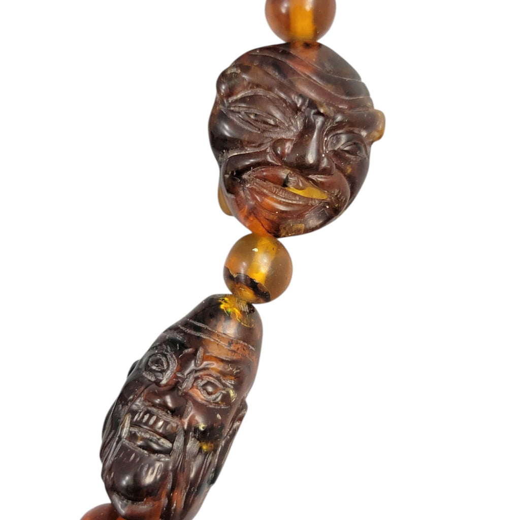 Chinese carved amber necklace with luohan heads and figural pendant, c. 1870
